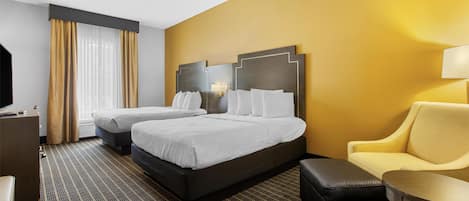 A hotel room with two beds, a sofa, a desk, and a lamp.