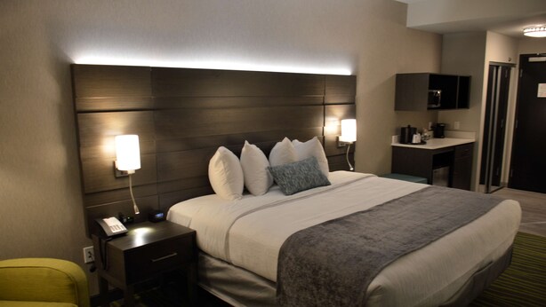 Une chambre d’hôtel avec un grand lit, des lampes de chevet, un bureau avec une chaise et un four à micro-ondes.