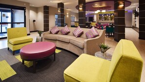 Un hall d’entrée avec un canapé, des fauteuils, une table et un coin bar.