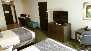 A hotel room with two beds, a desk with a computer, a television, a small table with a phone, and a chair.