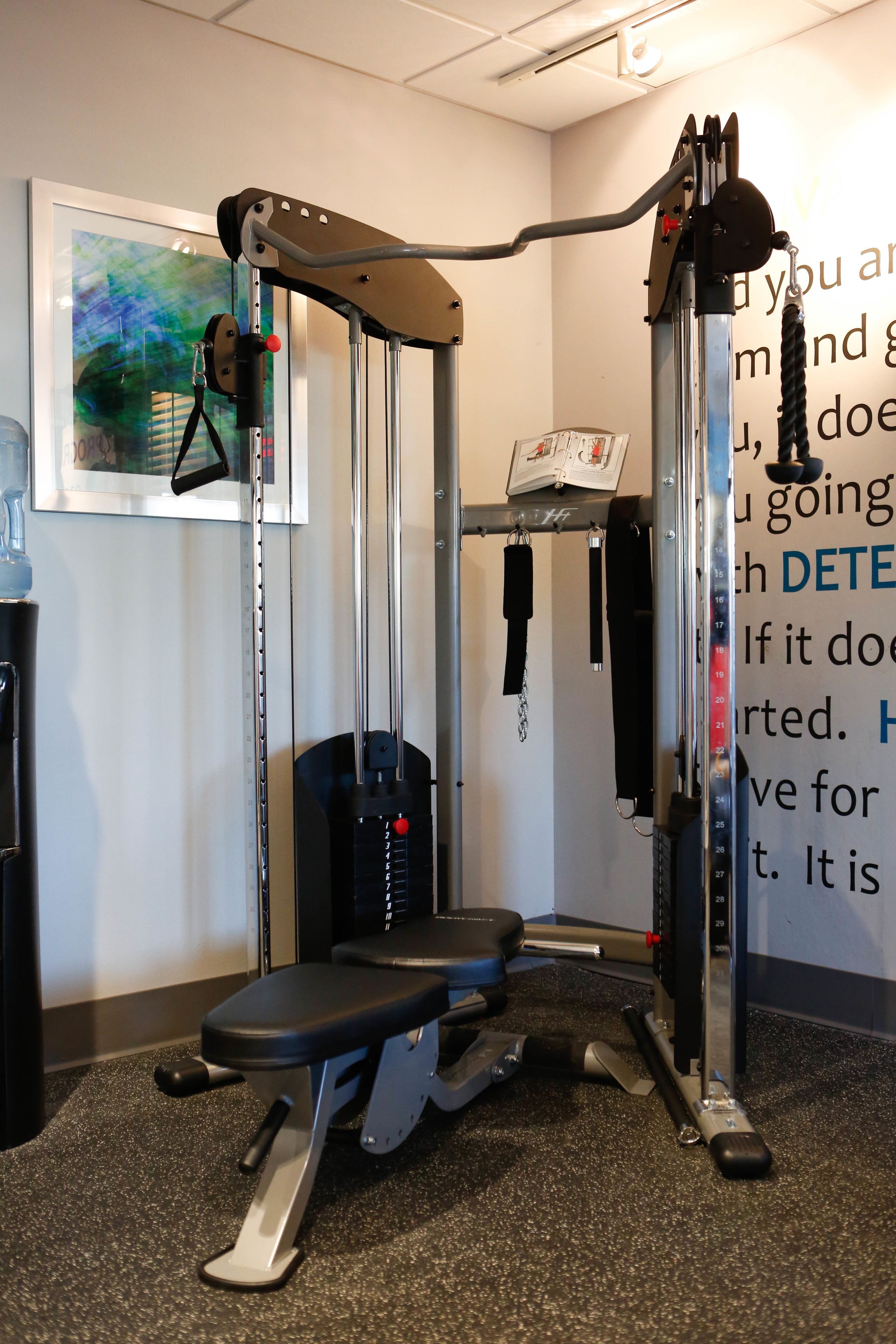 A gym with a bench, weight machine, and a motivational quote on the wall.
