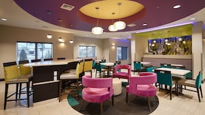 Un restaurant moderne doté d’un bar, de plusieurs types de sièges, notamment des banquettes et des tables, et d’un plafond au design original et dynamique.