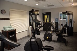 A gym with exercise equipment, a water cooler, and a towel rack.