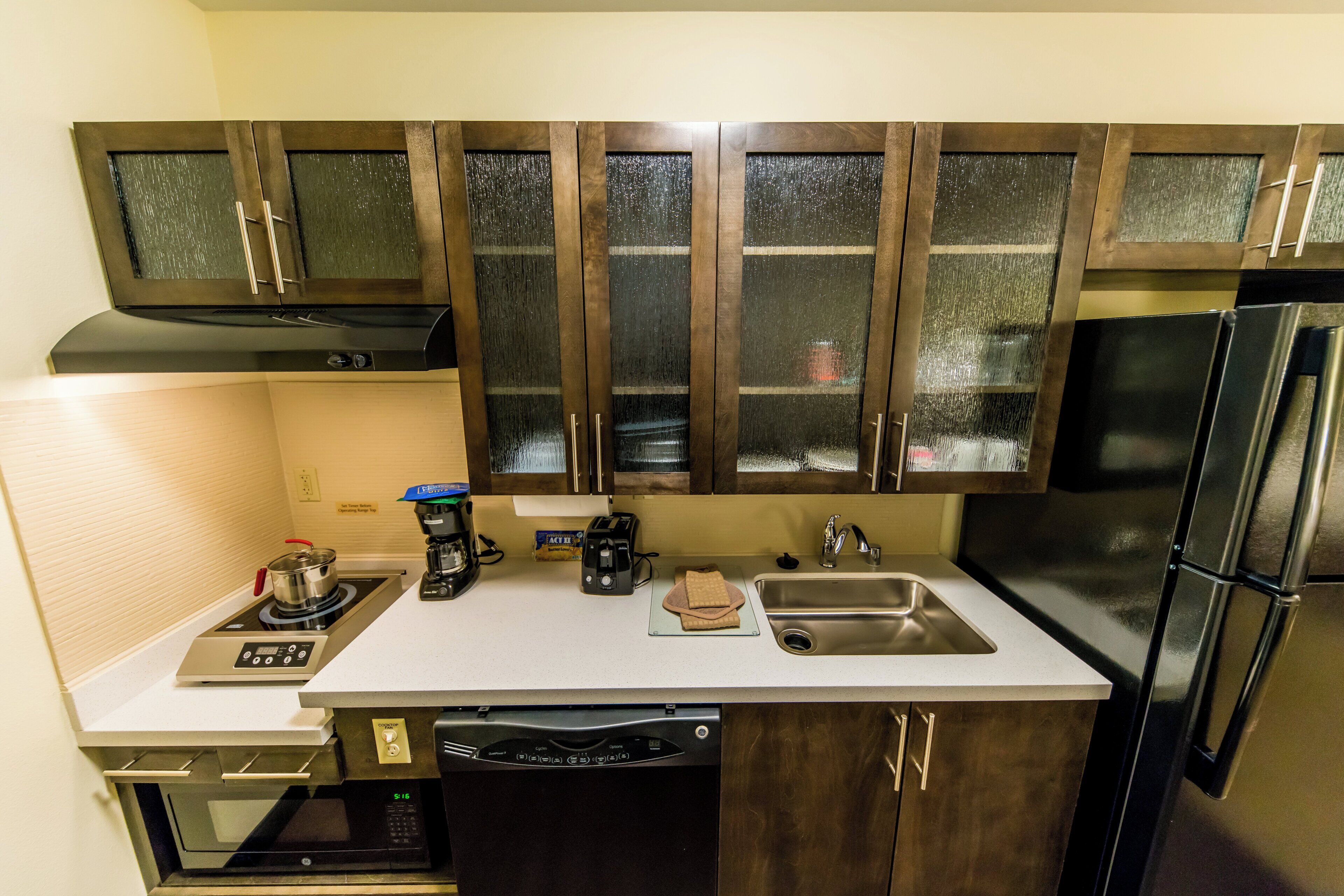 A kitchen with a built-in stove, a coffee maker, a toaster, a sink, and a dishwasher.