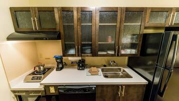 A kitchen with a built-in stove, a coffee maker, a toaster, a sink, and a dishwasher.