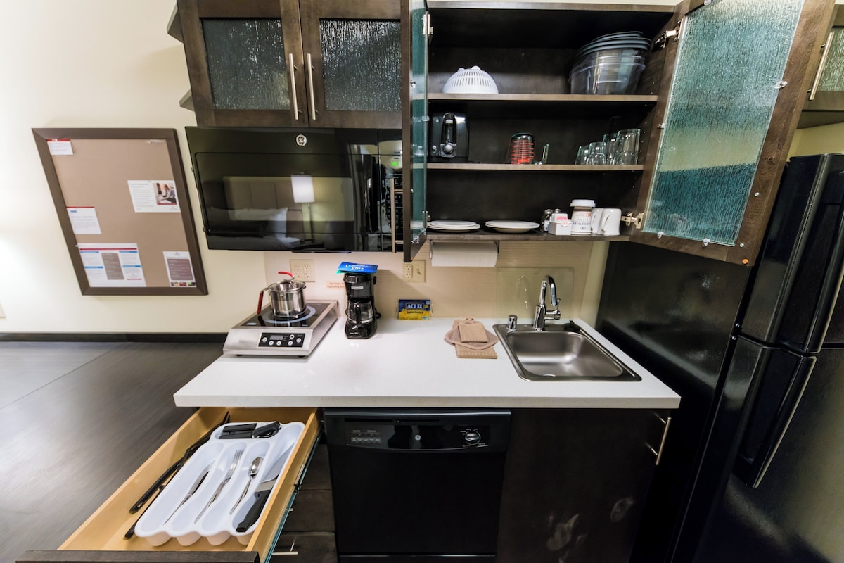 Una cocina compacta con lavavajillas integrado, cafetera y lavabo.
