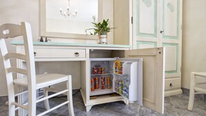 A compact kitchen with a small refrigerator stocked with beverages, a white chair, and a potted plant on the counter. - Morpheo Rooms (Alghero)