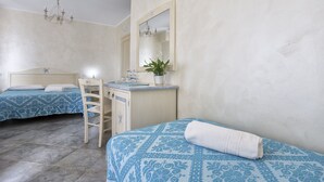 A bedroom with two beds, a desk, a chair, a mirror, and a chandelier. - Morpheo Rooms (Alghero)
