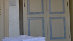 A room with a wardrobe featuring starfish designs, a stack of white towels, and a light switch on the wall. - Morpheo Rooms (Alghero)