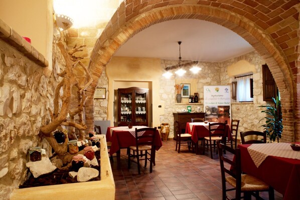 A rustic dining area with stone walls, wooden furniture, and a brick archway.