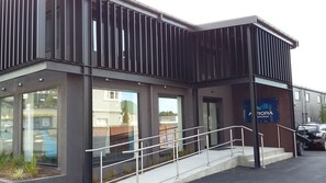 A modern building with large windows, a metal railing, and a sign that reads "A RORA GORGE". - Aurora On George (Dunedin)