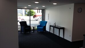 A room with two chairs, a small table, and a view of parked cars outside. - Aurora On George (Dunedin)