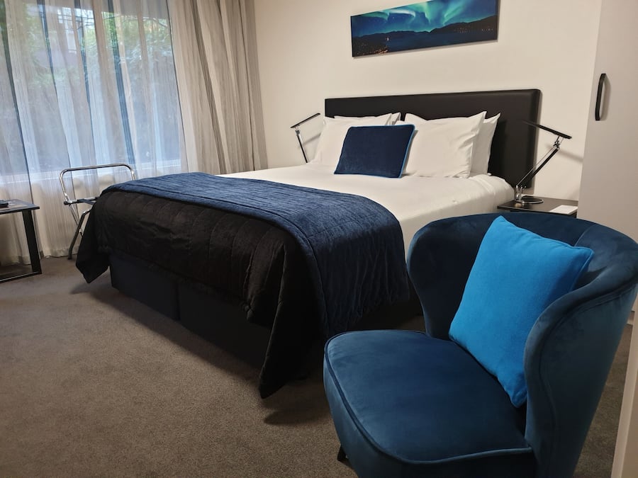 Ein Hotelzimmer mit Bett, Sessel, Schreibtisch und einem Bild an der Wand.