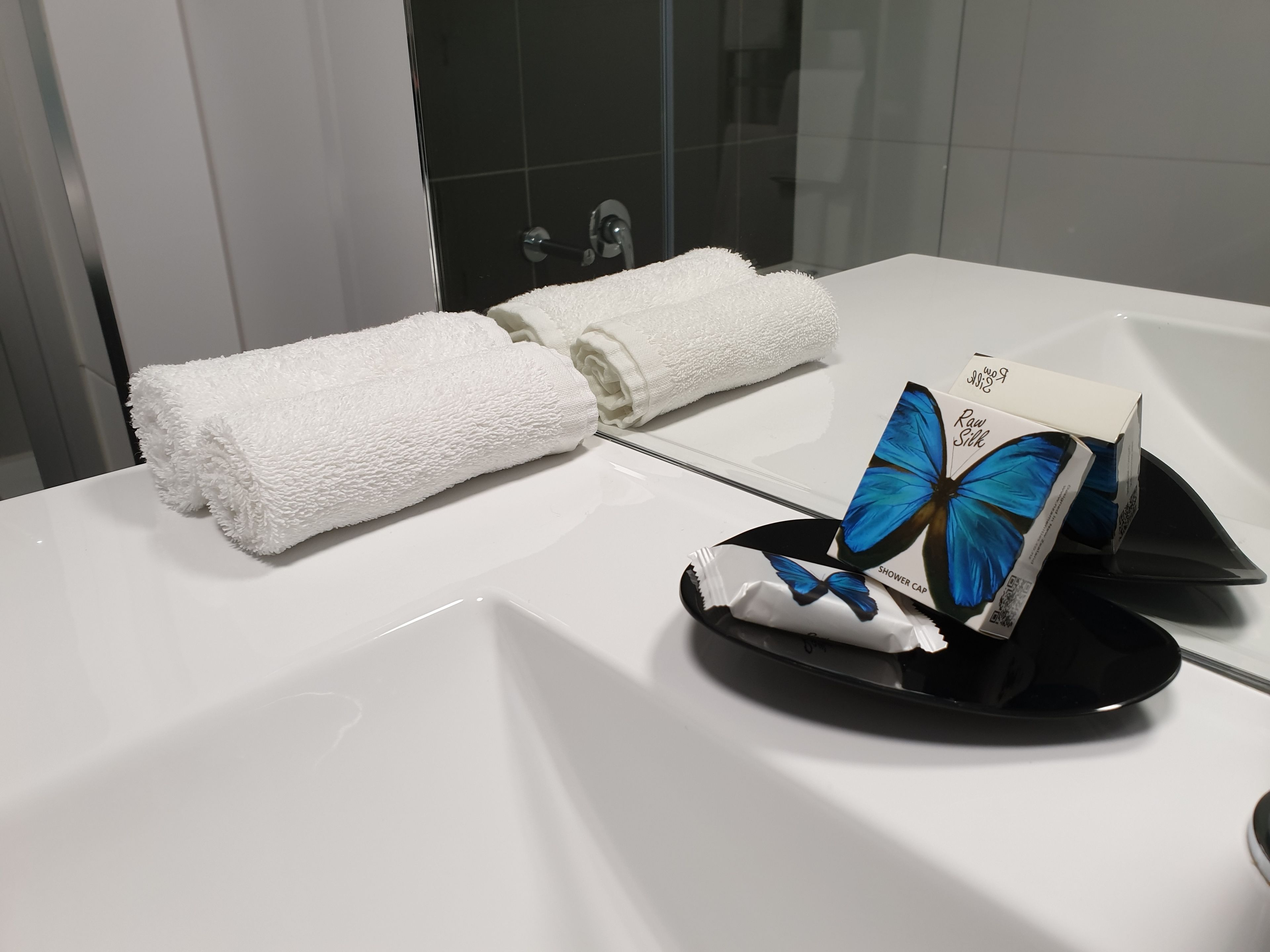 Un baño con un lavamanos blanco, una toalla y un gorro de ducha con un diseño de mariposa azul.