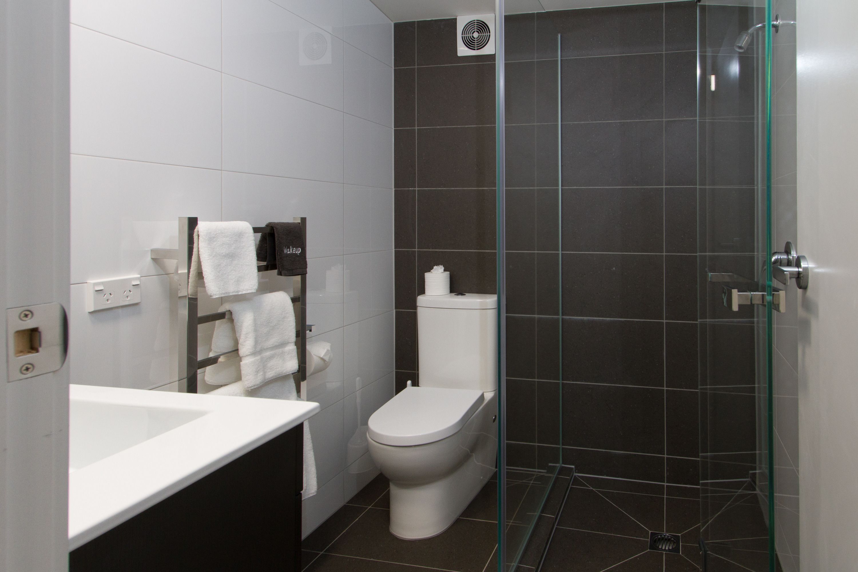 A modern bathroom with a white sink, toilet, and glass shower enclosure.
