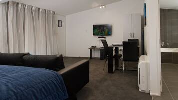 Una habitación de hotel moderna con una cama, un escritorio con una computadora, una silla y un televisor.