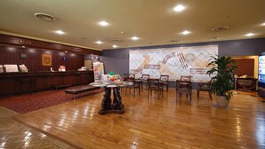 A hotel lobby with a reception desk, seating area, and a large decorative wall.