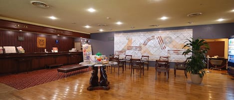 Un vestíbulo de hotel con una recepción, zona de estar y una gran decoración mural.