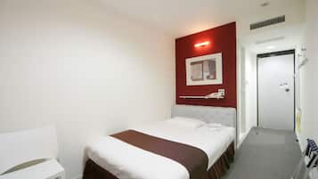 Una habitación de hotel con una cama, una silla blanca, una pared de acento roja y una puerta.
