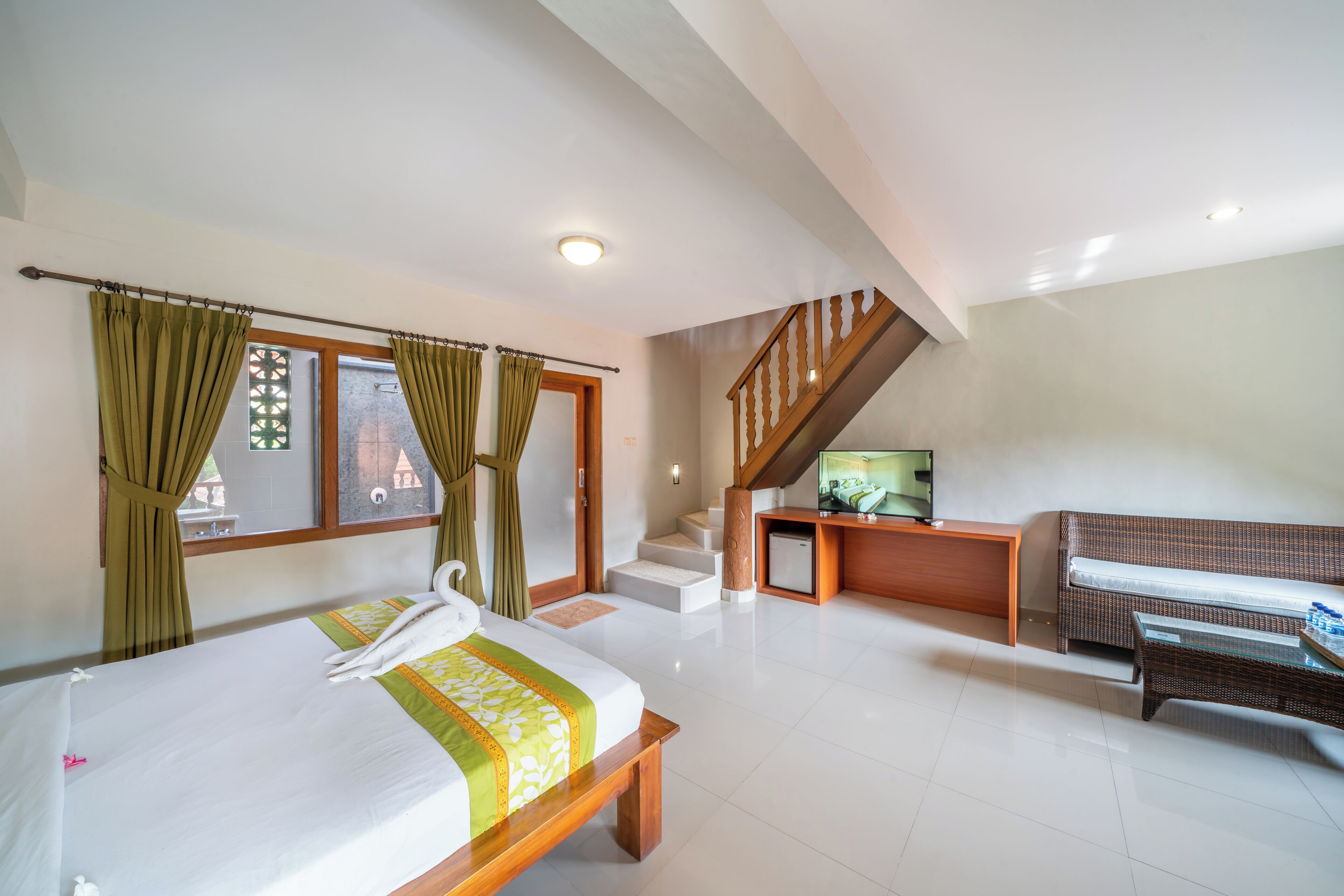 Una habitación de hotel con cama, sofá, televisor y escalera.