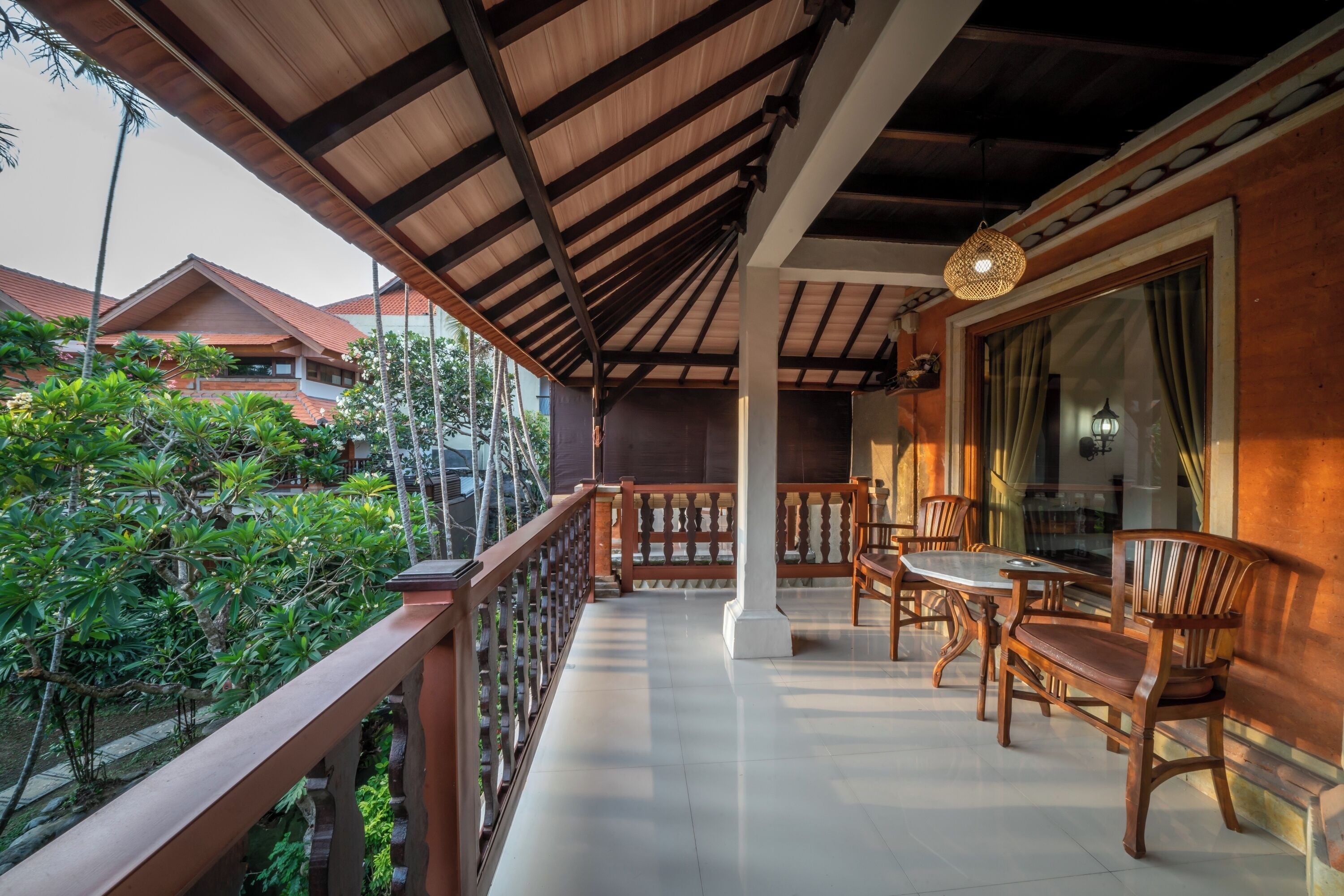 A balcony with wooden furniture and a view of the surrounding greenery and buildings.