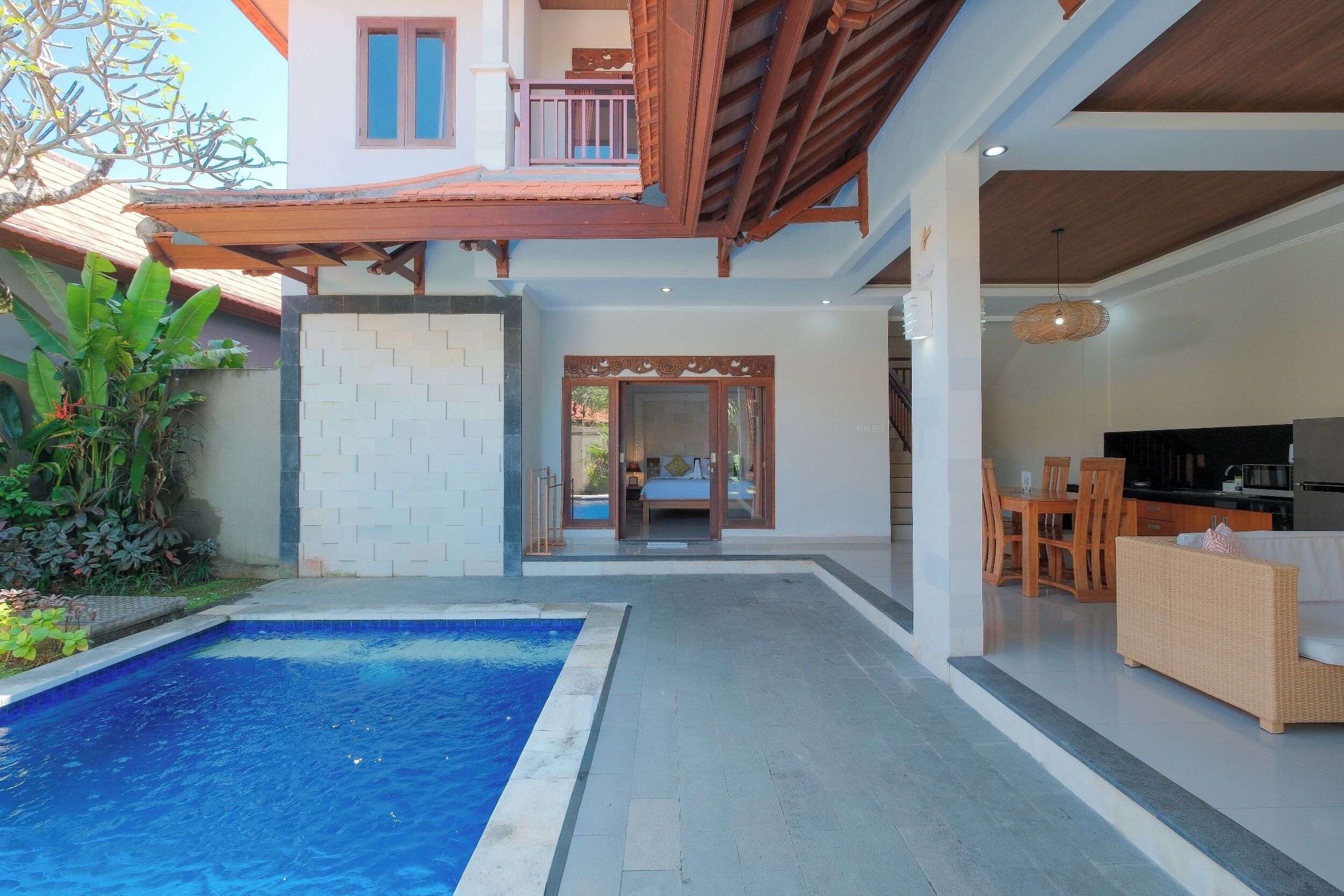 A modern villa with a swimming pool, a dining area, and a bedroom with a balcony.