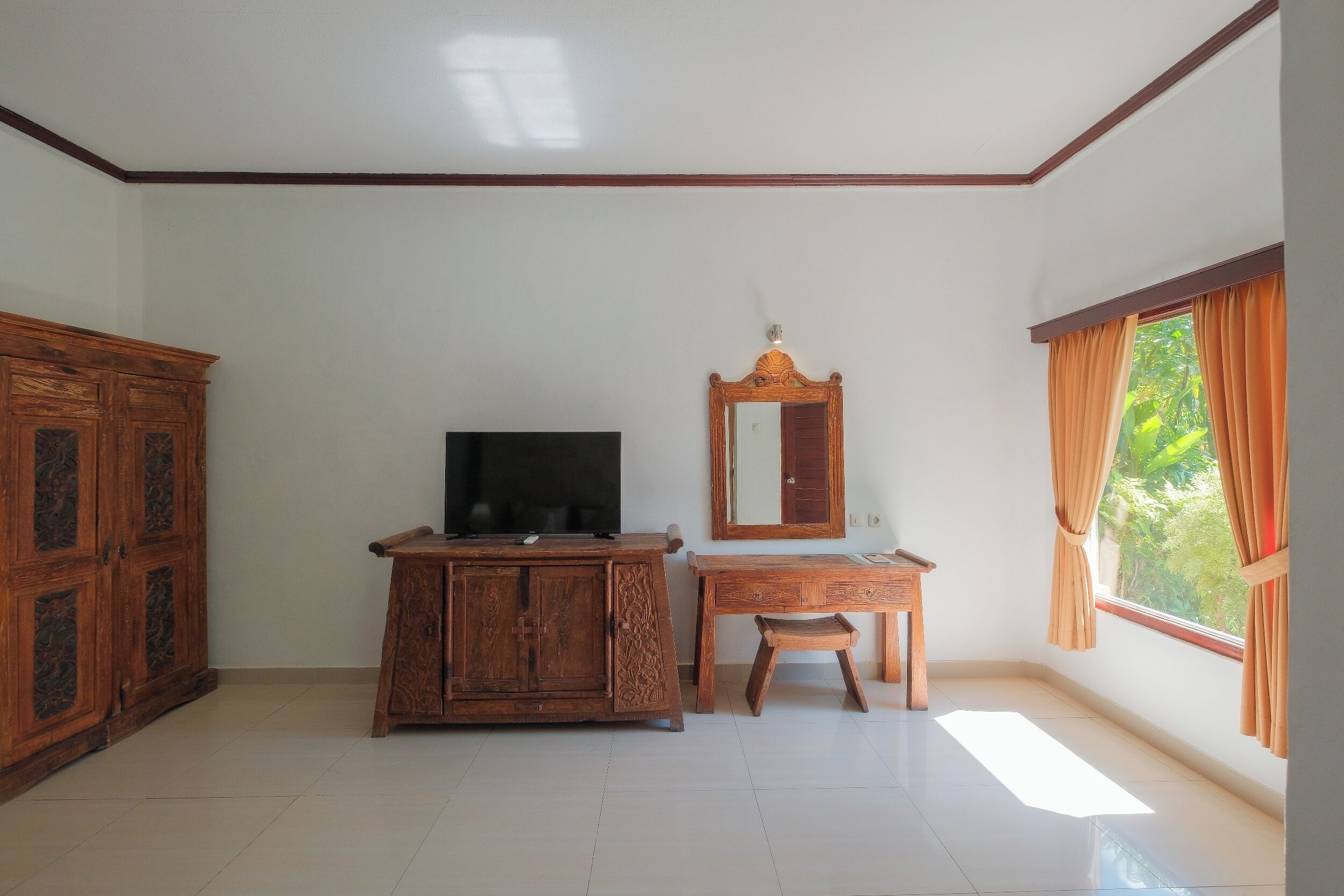A room with a wooden cabinet, a television, a desk, and a mirror.