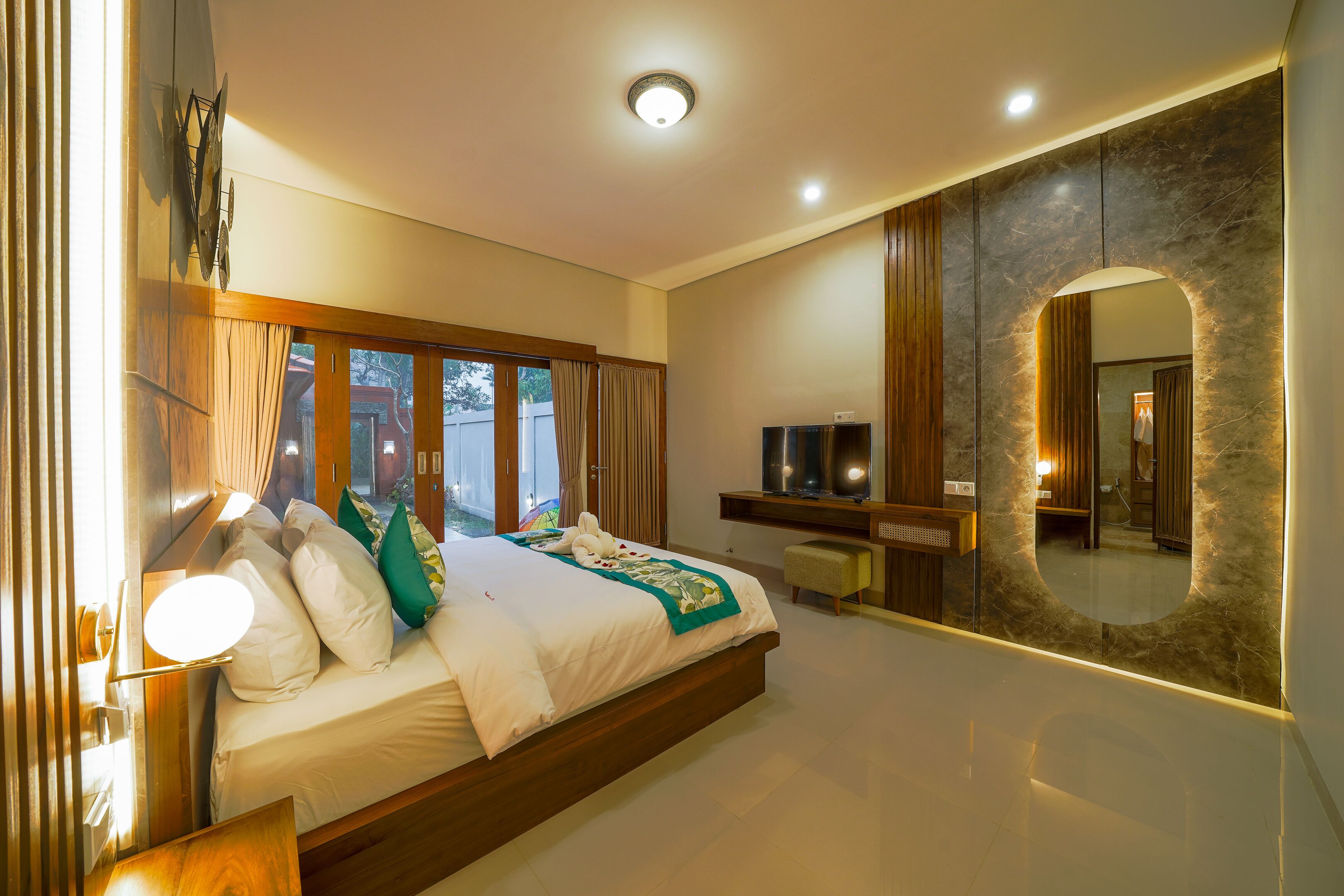 Un dormitorio moderno con una cama grande, televisión y espejo.