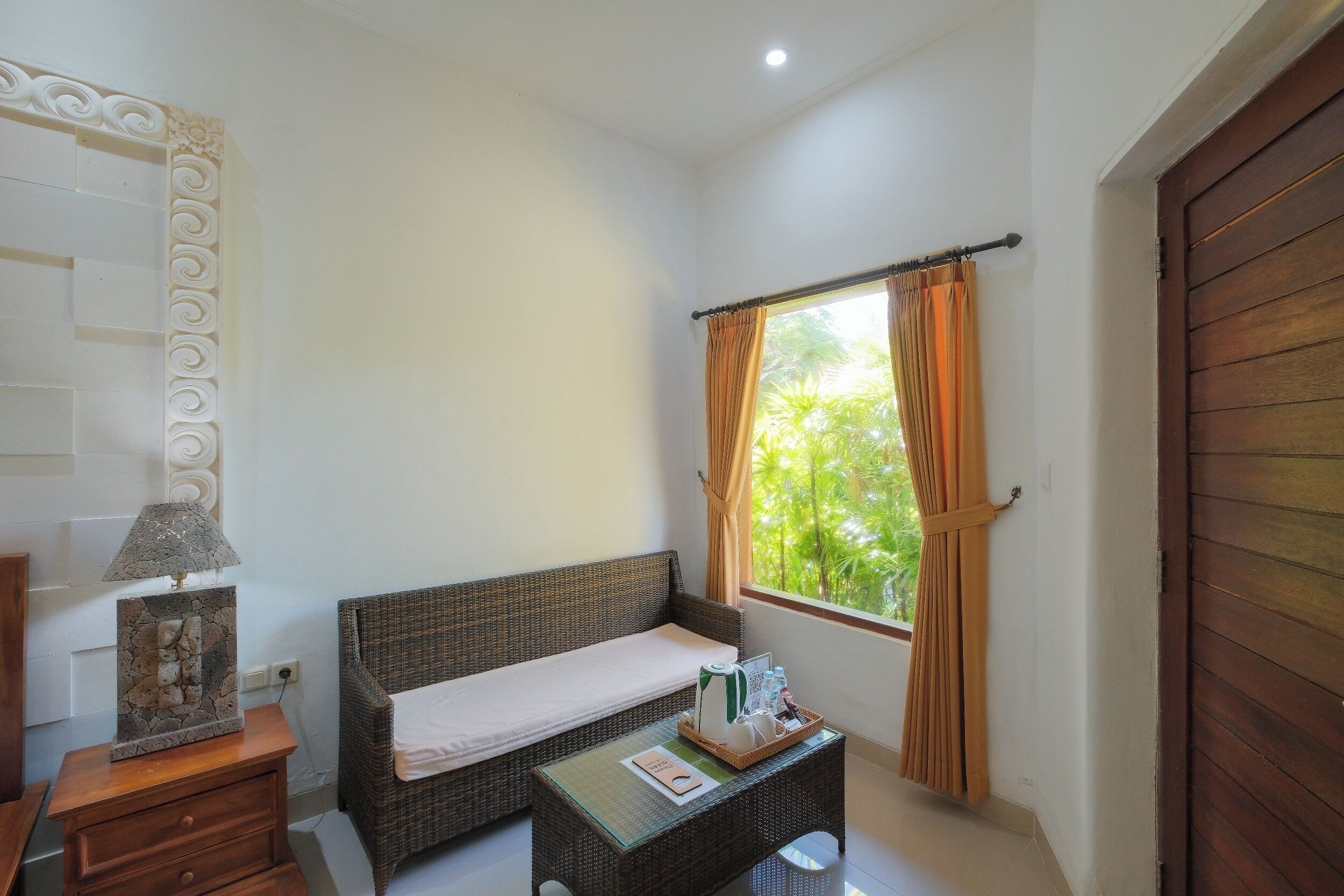 A room with a bed, a small table with a tray, a lamp, and a window with curtains.