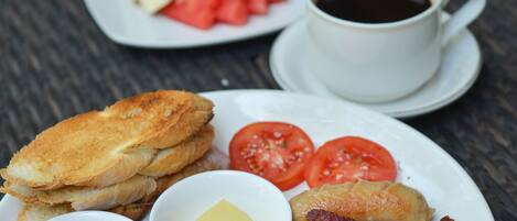 Une assiette de petit-déjeuner avec des œufs, du bacon, des tomates, des toasts et une tasse de café.