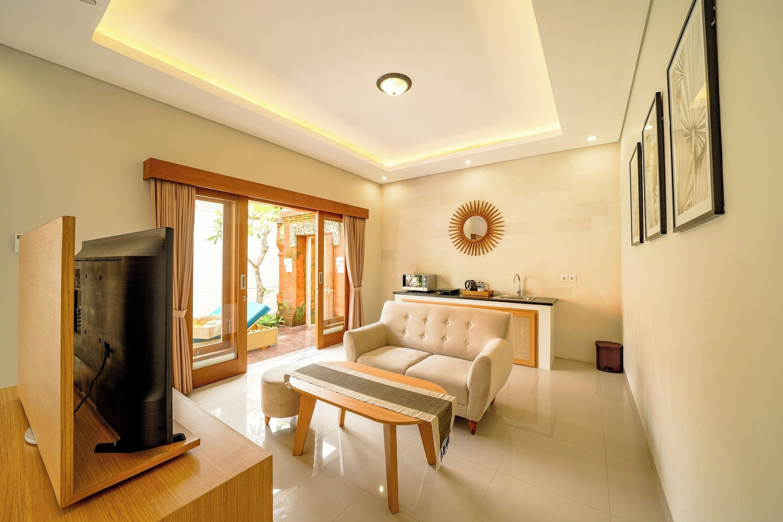 A modern living room with a sofa, a coffee table, a TV, and a dining area with a kitchen counter.