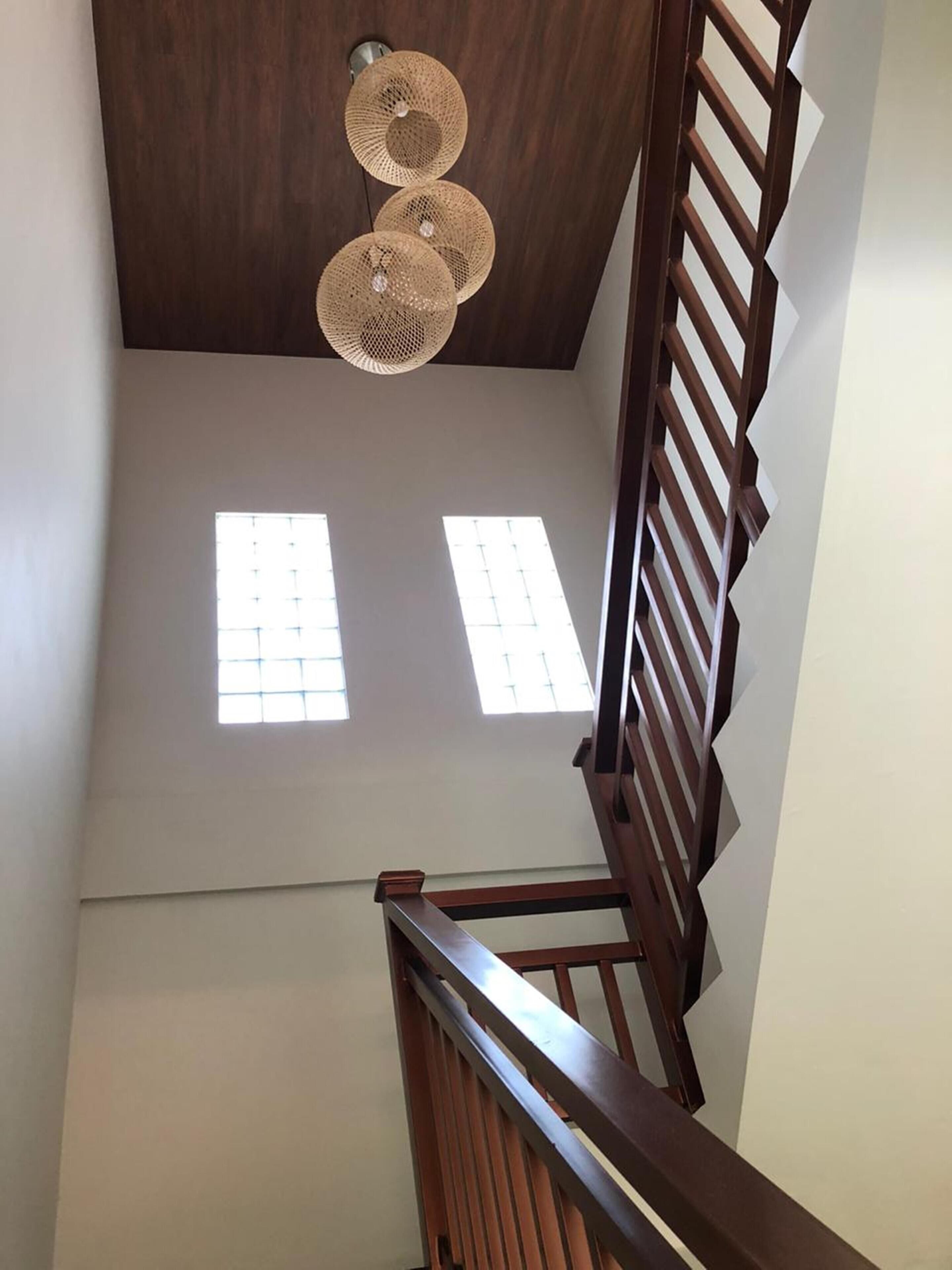 A staircase with wooden railings and a ceiling fan. There are two windows on the wall.