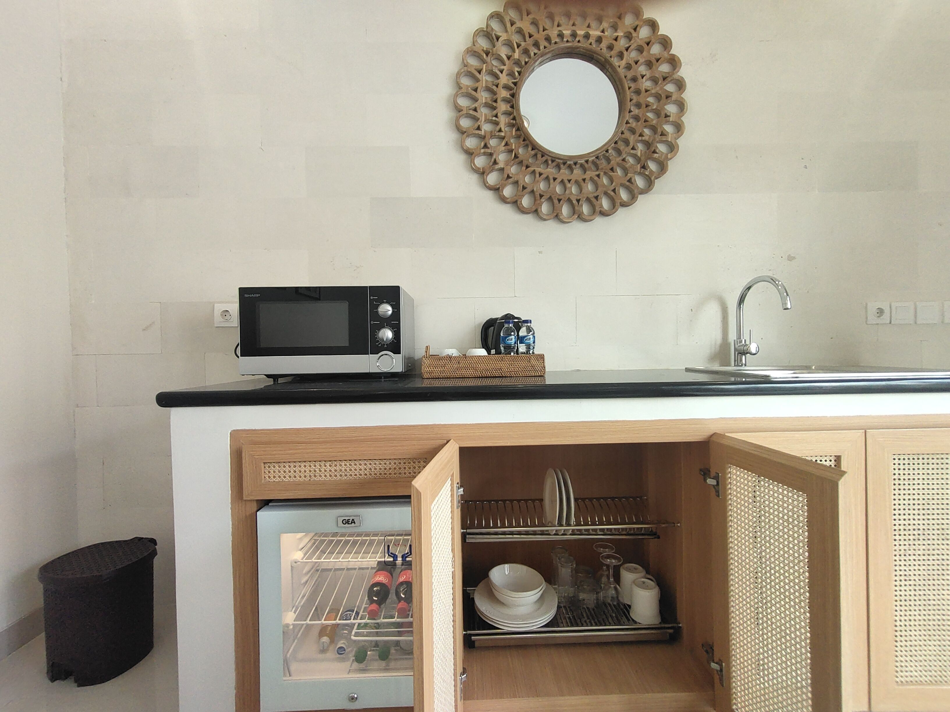 Una cocina compacta con microondas, lavamanos y nevera integrada.