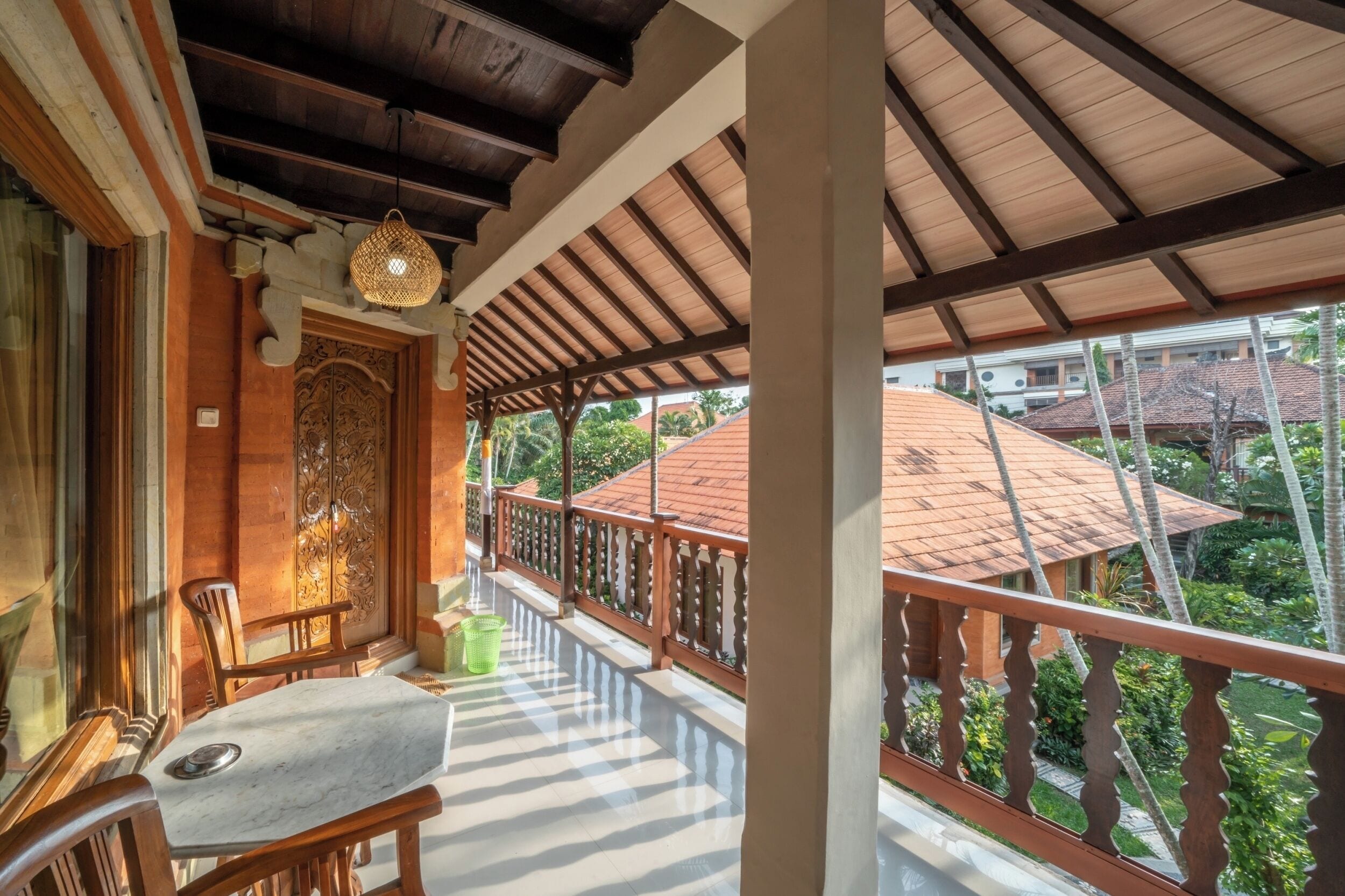A balcony with wooden railings, a table, chairs, and a decorative hanging light fixture.