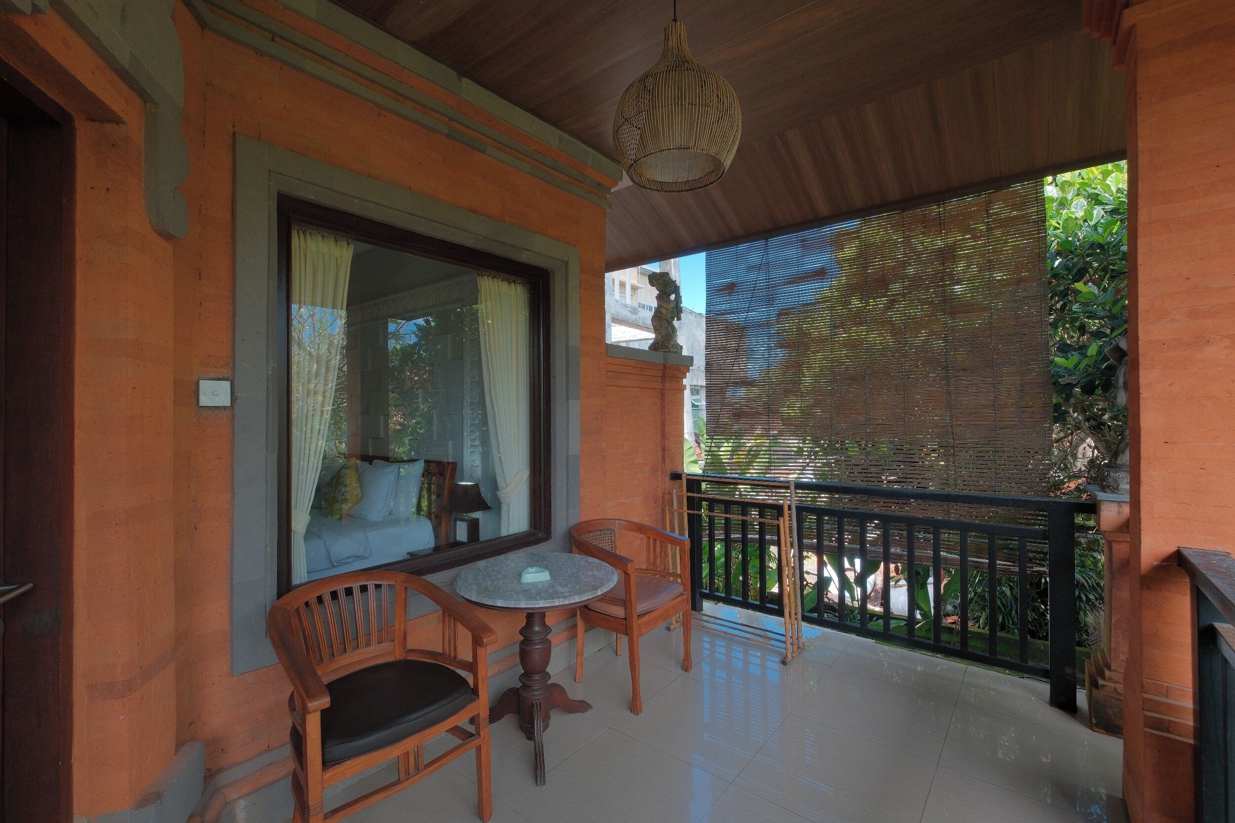 Un balcón con una mesa y sillas de madera, una lámpara colgante y vistas al verdor.