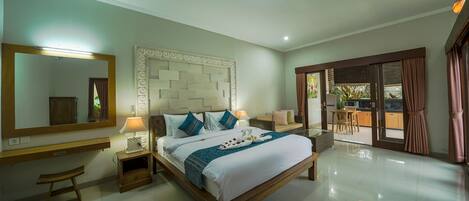 A spacious bedroom with a large bed, bedside tables, a mirror, and a view of the outdoor area.