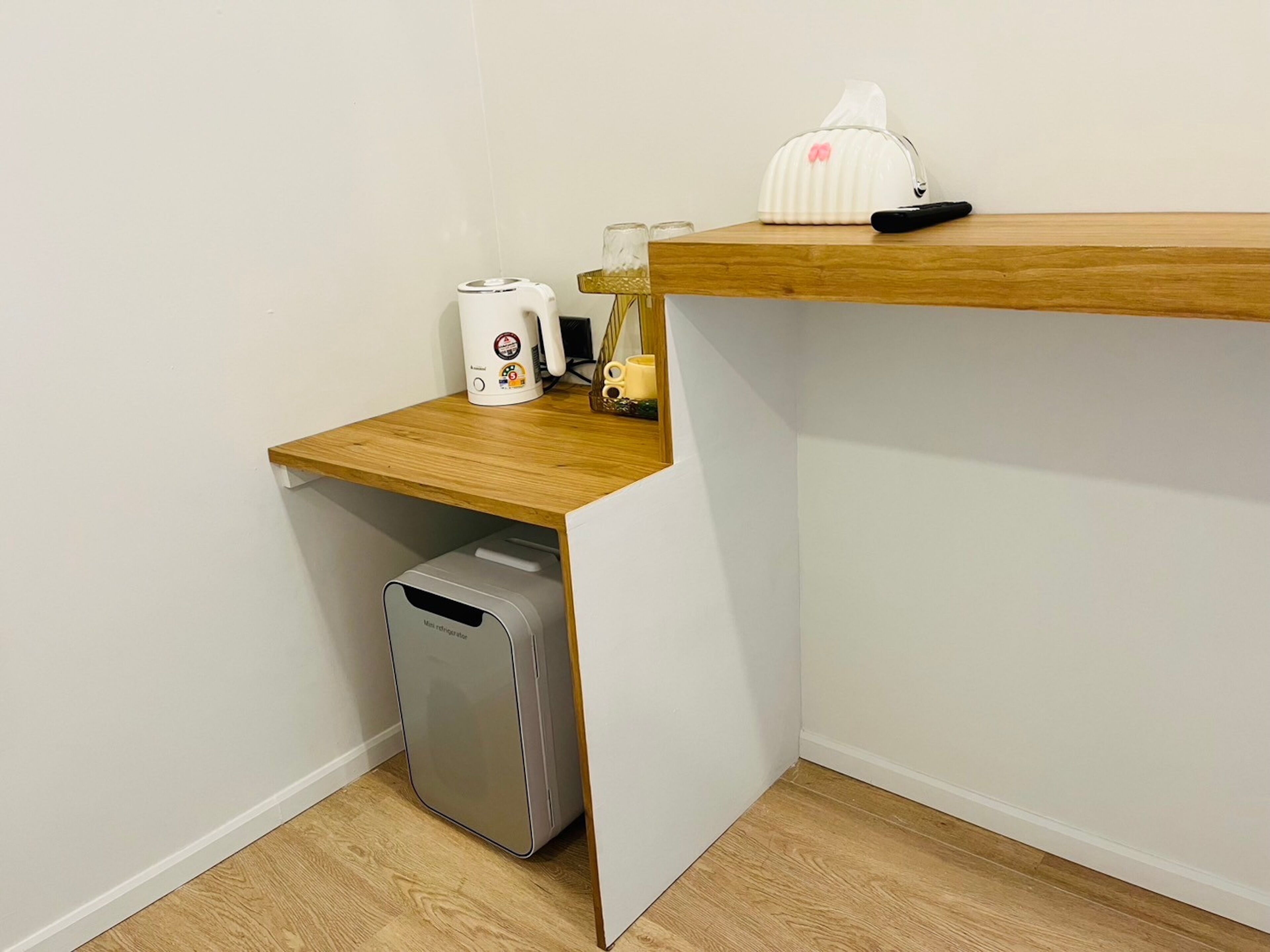 A compact kitchenette with a wooden countertop, a coffee maker, a tissue box, and a mini refrigerator.