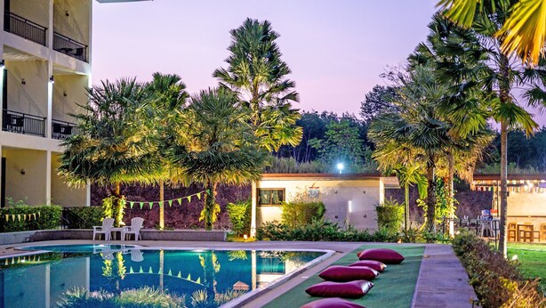 A pool area with a clear pool, lounge chairs, and a building with balconies. - Takhun Mountain View Hotel (Ban Ta Khun)