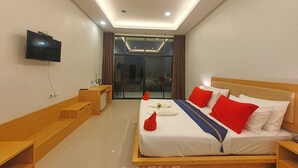 A modern hotel room with a large bed, a TV, a desk, and a view through a glass door. - Takhun Mountain View Hotel (Ban Ta Khun)