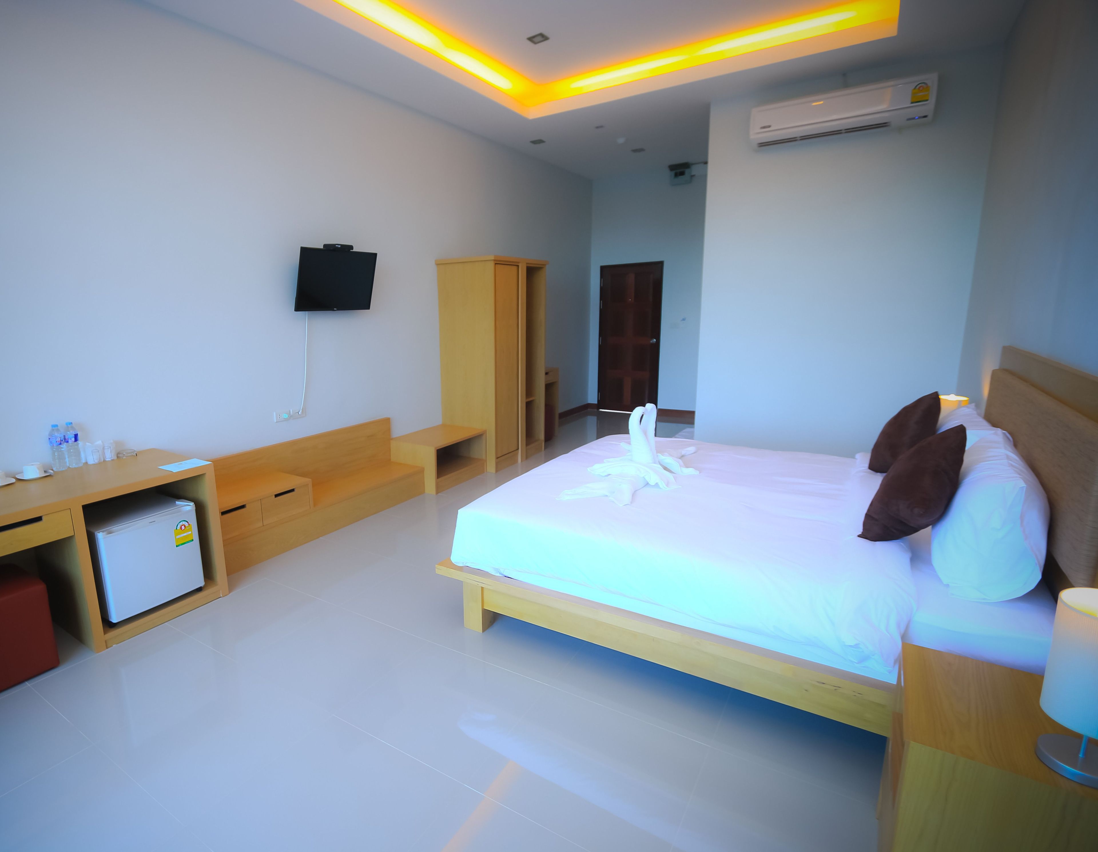 A hotel room with a bed, a desk, a television, and an air conditioning unit.