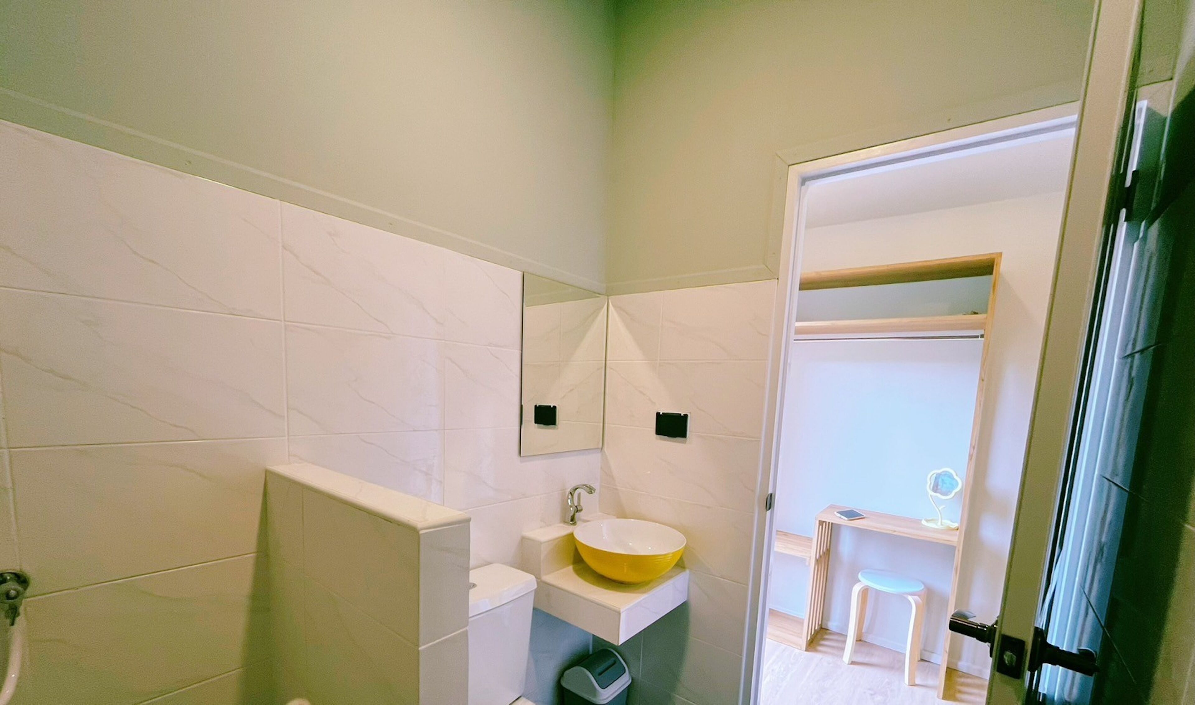 Un baño pequeño con un lavamanos blanco, un espejo y un taburete.