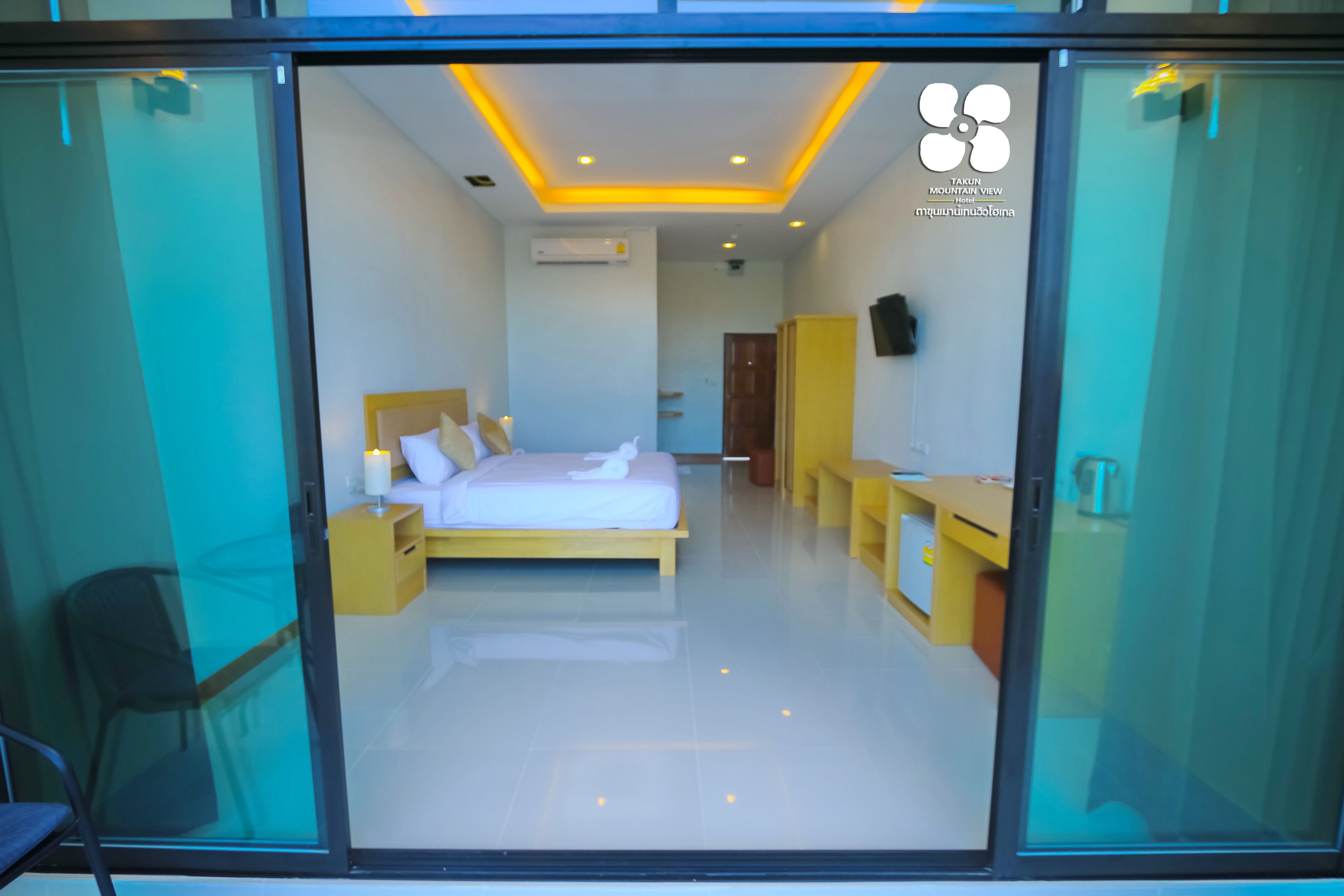 A modern hotel room with a bed, bedside table, and a desk.