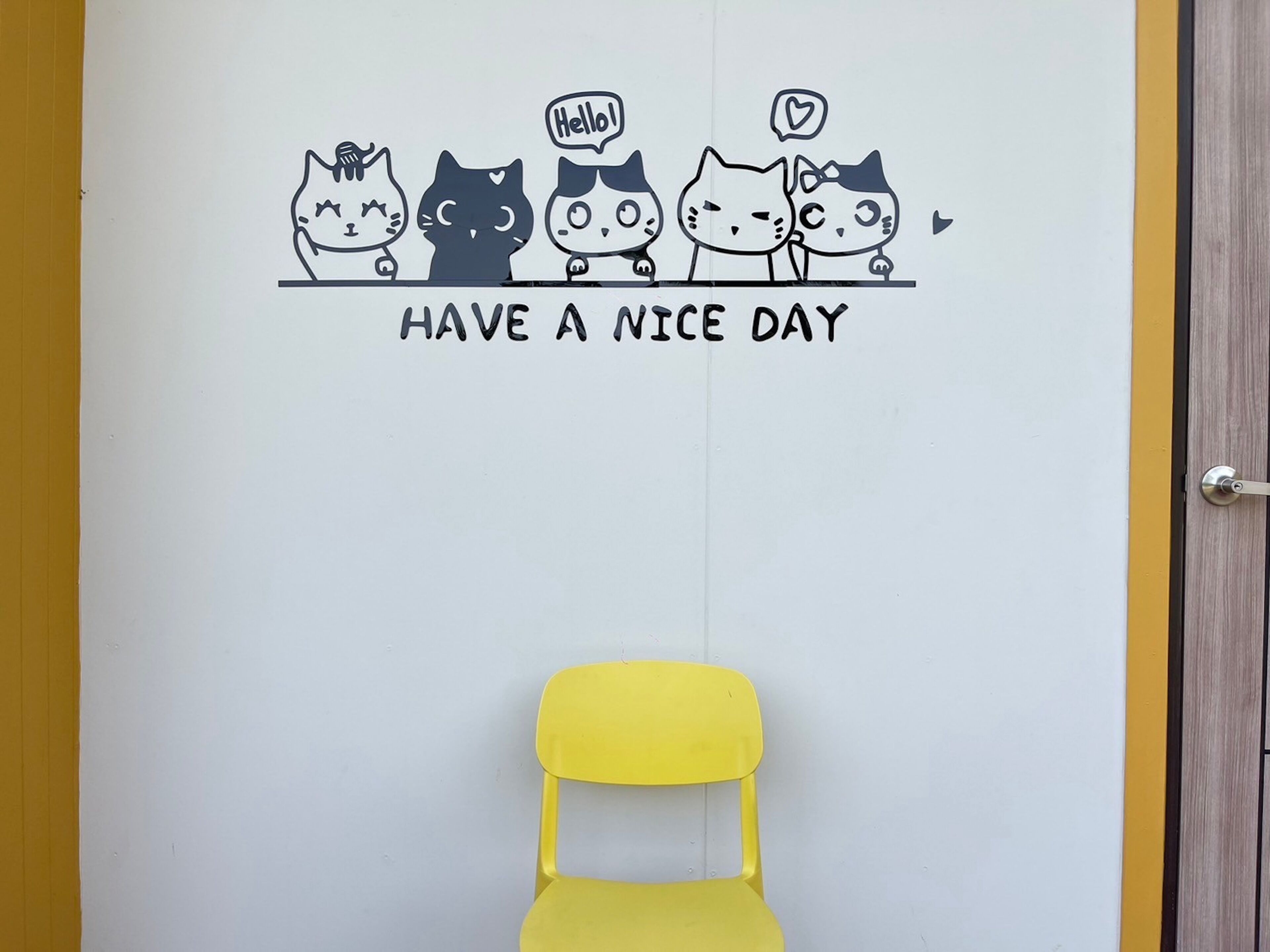 A door with a cheerful wall decal of four cats and the text "HAVE A NICE DAY".