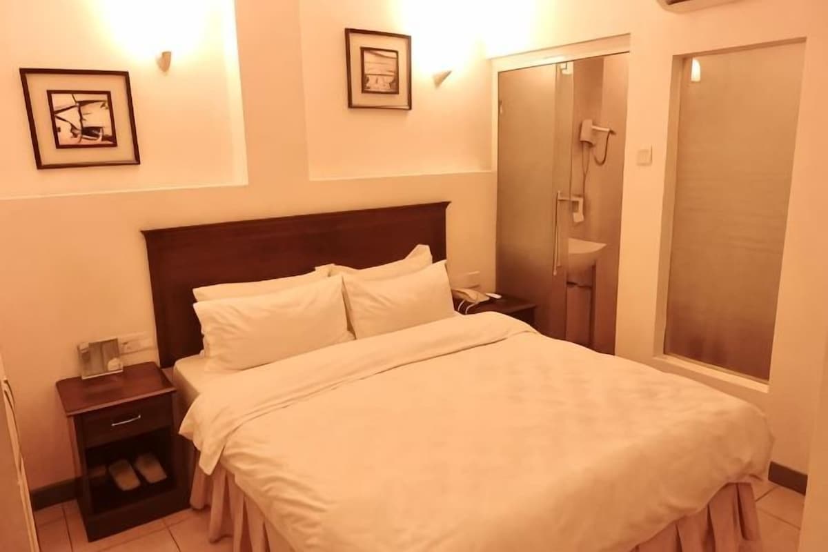 Une chambre d’hôtel avec un lit, une table de chevet et un espace douche.