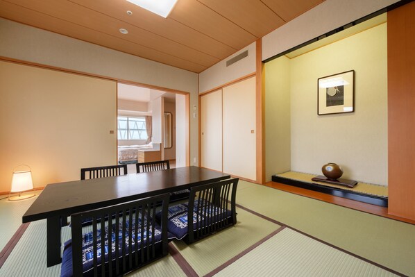 A traditional Japanese-style room with tatami flooring, a low table with chairs, and a sliding door.