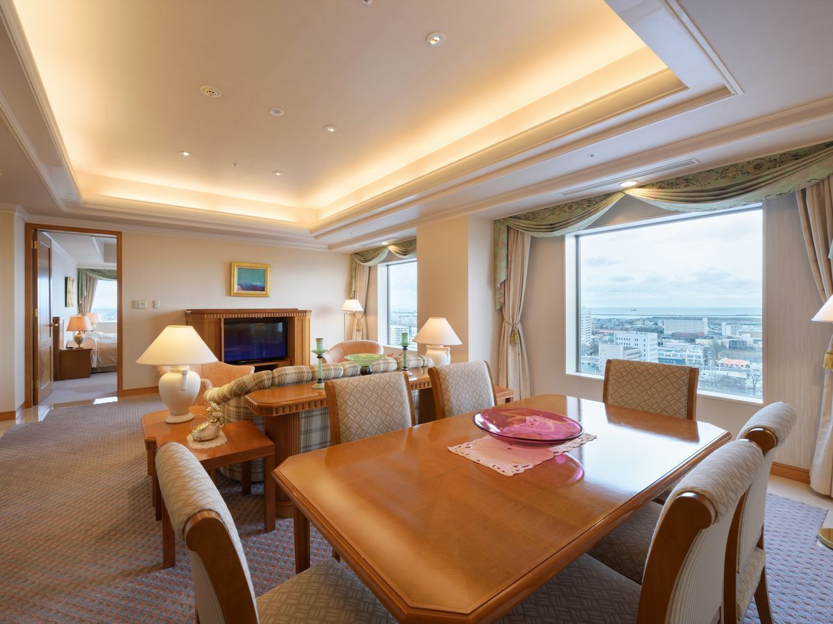Ein Hotelzimmer mit Essbereich, Fernseher und Blick auf die Stadt.
