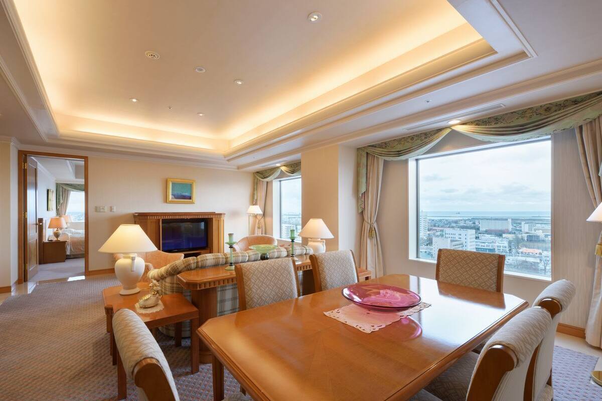 Ein Hotelzimmer mit Essbereich, Fernseher und Blick auf die Stadt.