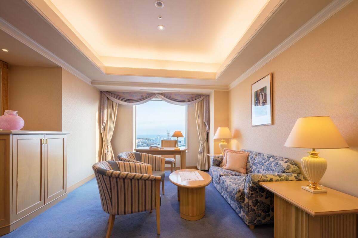 A hotel room with a sofa, armchair, and a small table.