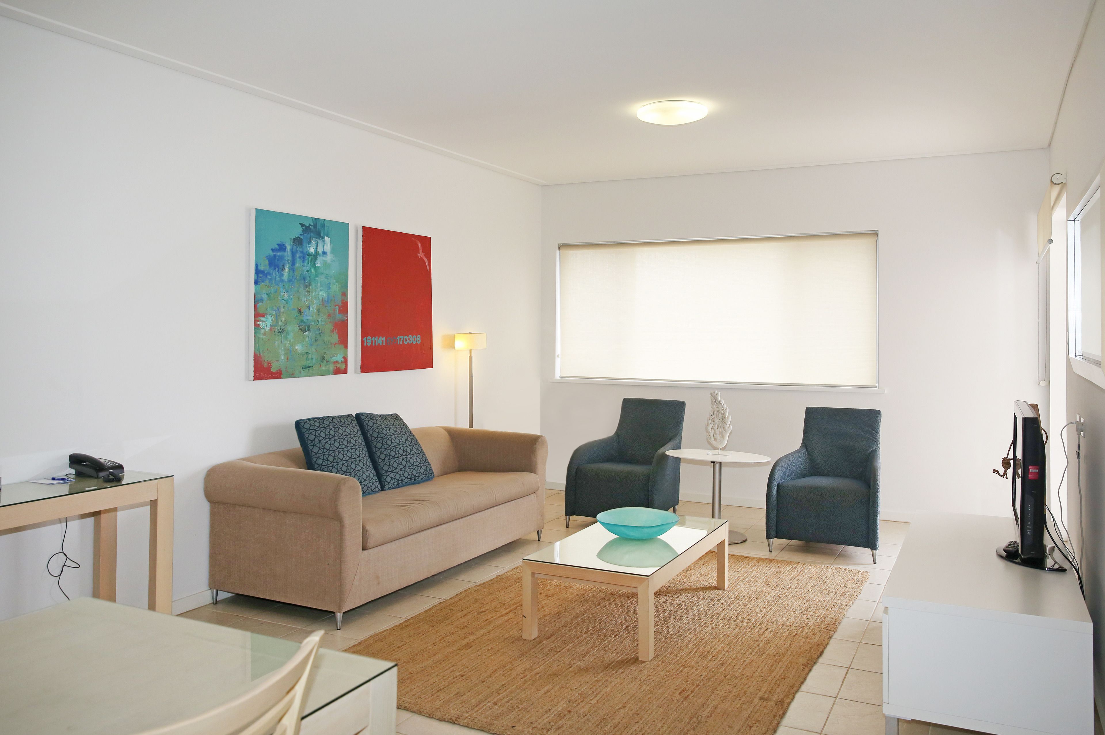 Un salon moderne comprenant un canapé, deux fauteuils, une table basse et un téléviseur.