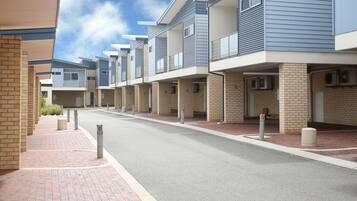 Una hilera de casas urbanas modernas con fachadas de ladrillo y balcones, un sendero pavimentado y bollards a lo largo de la calle.